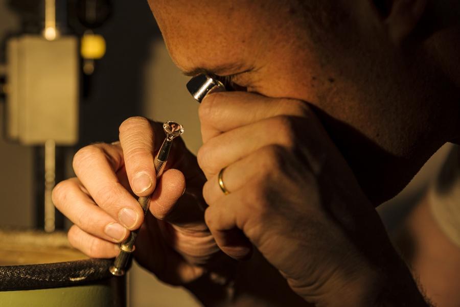 Mann analysiert Diamant mit Lupe - Diamantzertifikate