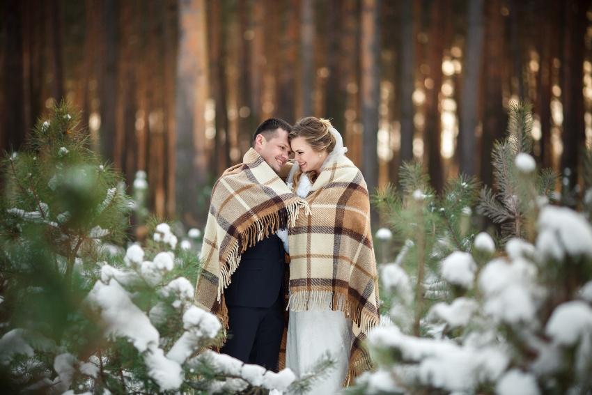 Junes Ehepaar in winterlichem Wald, in Decken eingehüllt