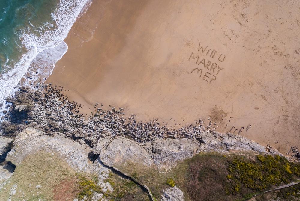 Schriftzug "Will you marry me" am Sandstrand
