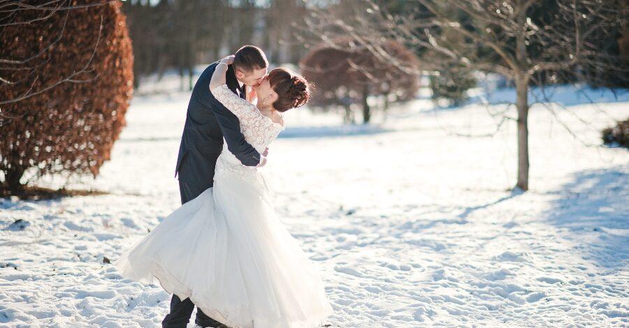 Hochzeitspaar küsst sich im Schnee - Hochzeit im Dezember