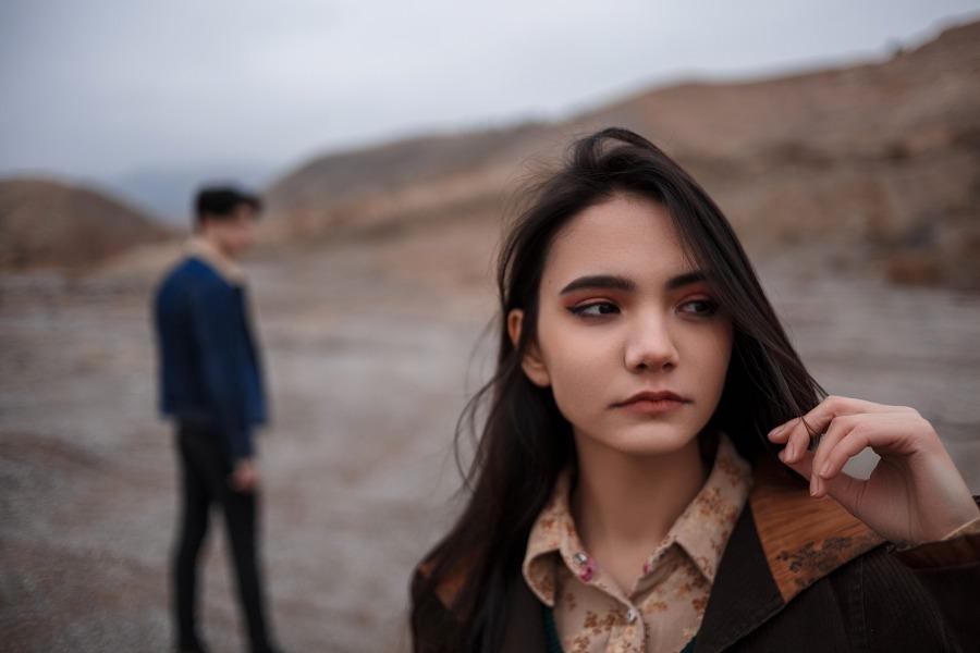Junge Frau blickt traurig, im Hintergrund ihr Partner, Symbolbild für eine Trennung - Verlobung aufgelöst