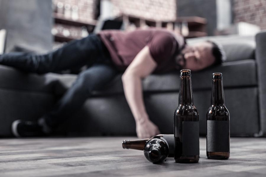 Mann schläft auf Couch -im Vordergrund Bierflaschen