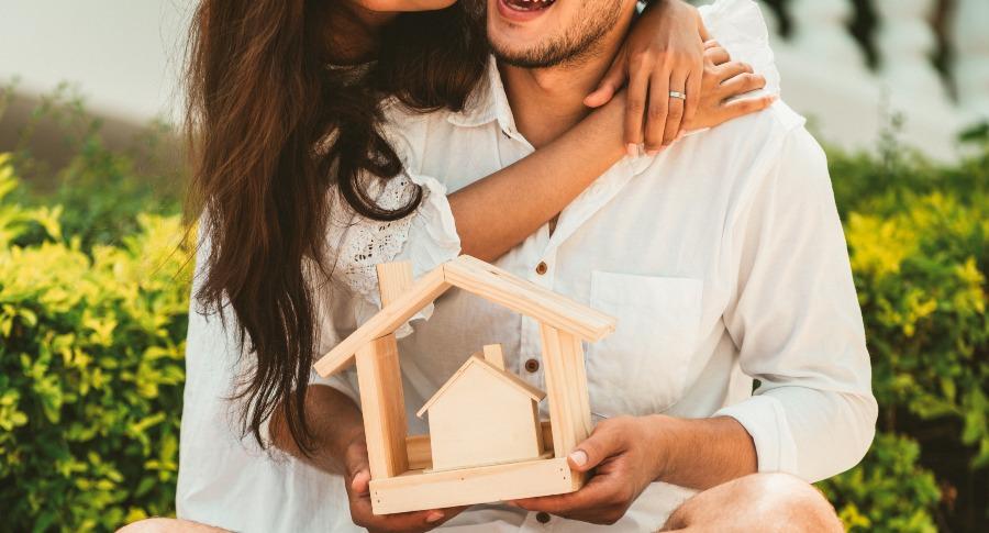 Junges Paar mit Holzhaus in der Hand - Konzept einer gemeinsamen Zukunft
