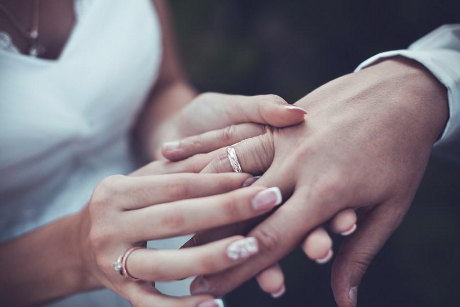 Frau steckt Ehering an Finger des Ehemanns - Ehering-Preise variieren stark