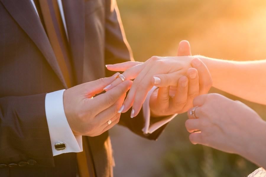 Mann steckt Ehering an Finger der Braut