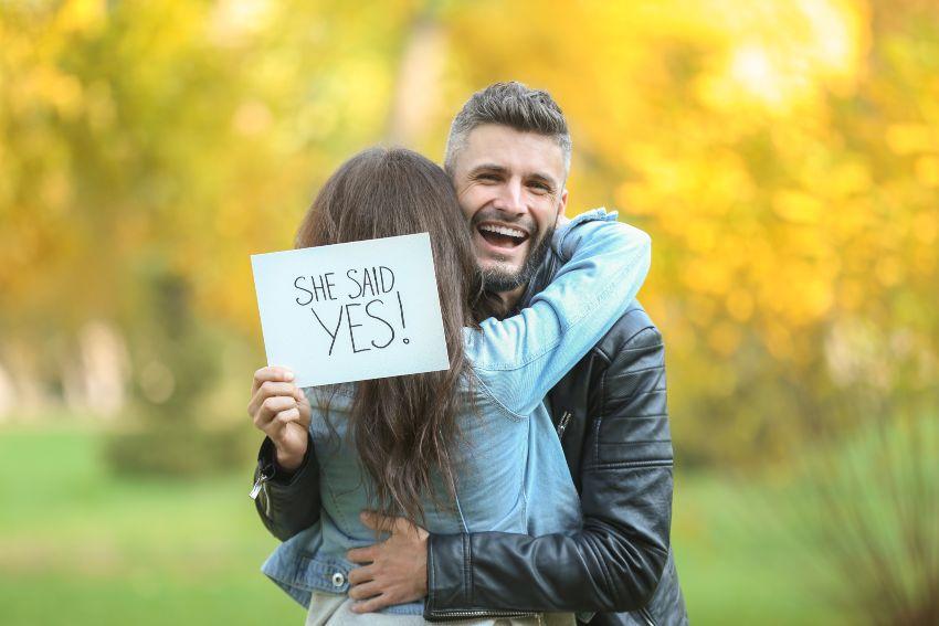 Paar nach der Verlobung, Mann hält Schild in der Hand "She Said Yes"