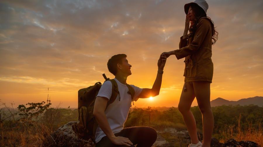 Junger Mann macht Freundin bei Sonnenuntergang Heiratsantrag ohne Ring